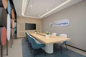 A modern meeting room with a long table, blue chairs, a white accent wall, and a logo. - Home Inn (Dongchuan Branch, Chiyang Street, Sanyuan County, Xianyang City) (Sanyuan)