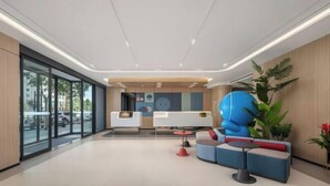 A modern lobby with a reception desk, seating area, and large windows.