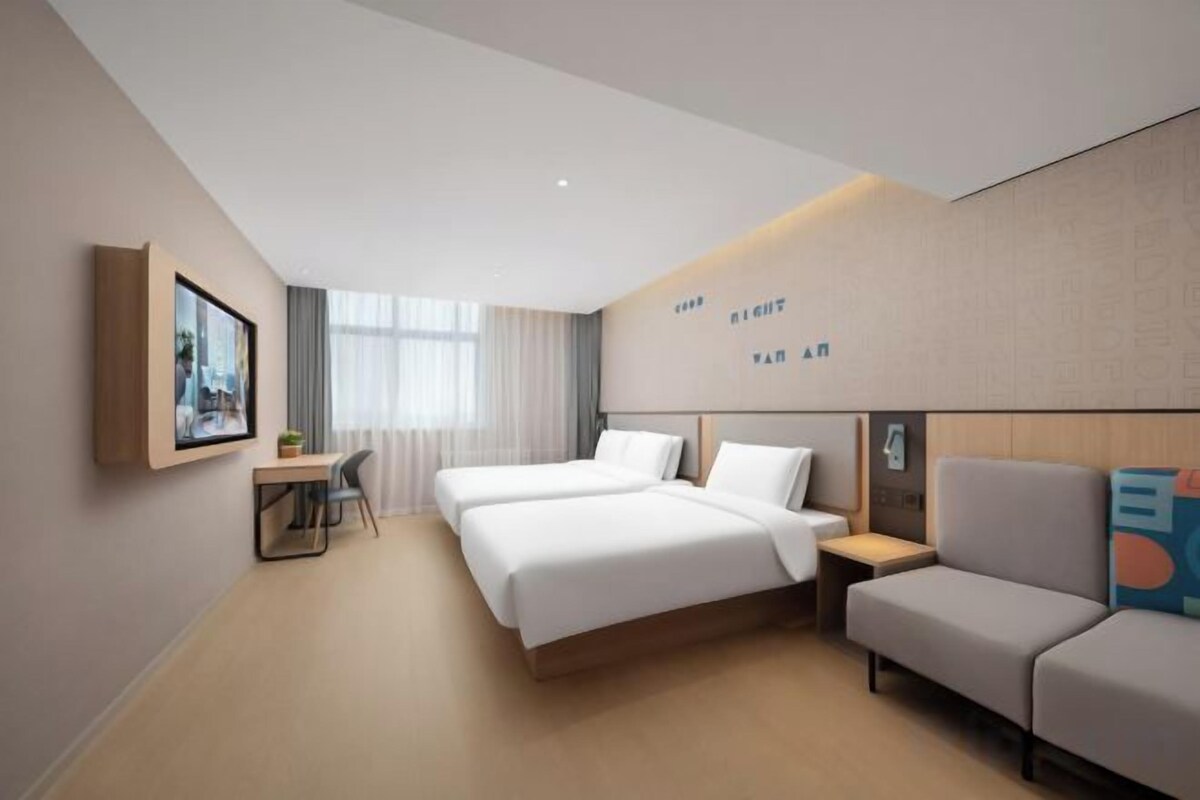 A modern hotel room with a bed, a sofa, a desk, and a chair.
