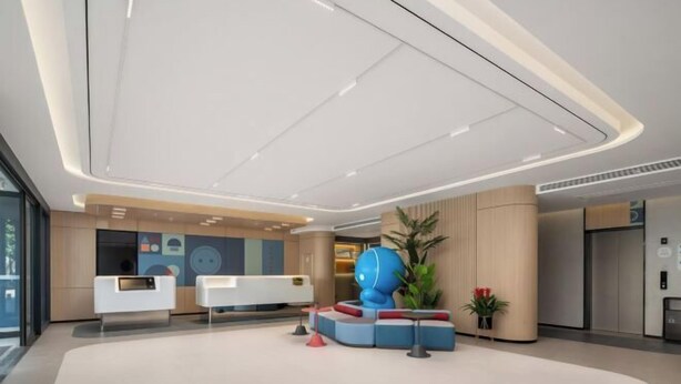 A modern reception area with a white reception desk, a large blue sculpture, and a potted plant.