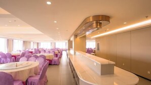 Un vestíbulo de hotel con mesas redondas, sillas con tapicería morada, un mostrador de recepción y un diseño de techo moderno.