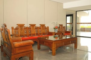 A traditional wooden dining table with chairs, a glass top, and a vase with flowers.