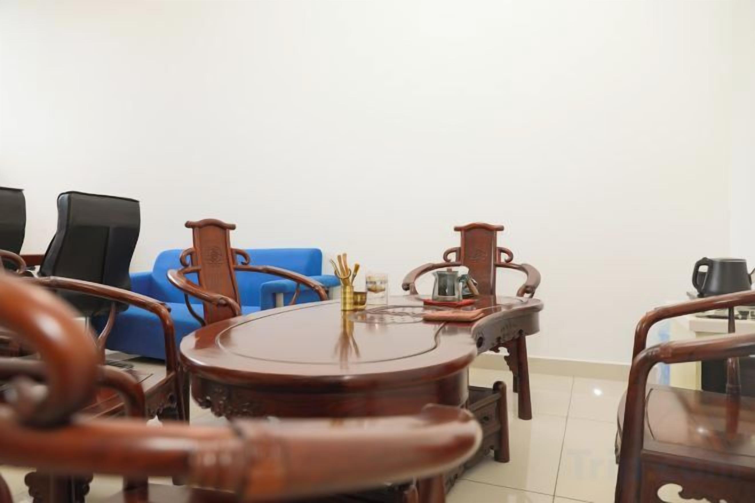 Una habitación con una mesa redonda de madera, dos sillas, un sofá azul y una cafetera.