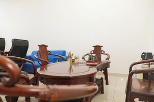 Una habitación con una mesa redonda de madera, dos sillas, un sofá azul y una cafetera.