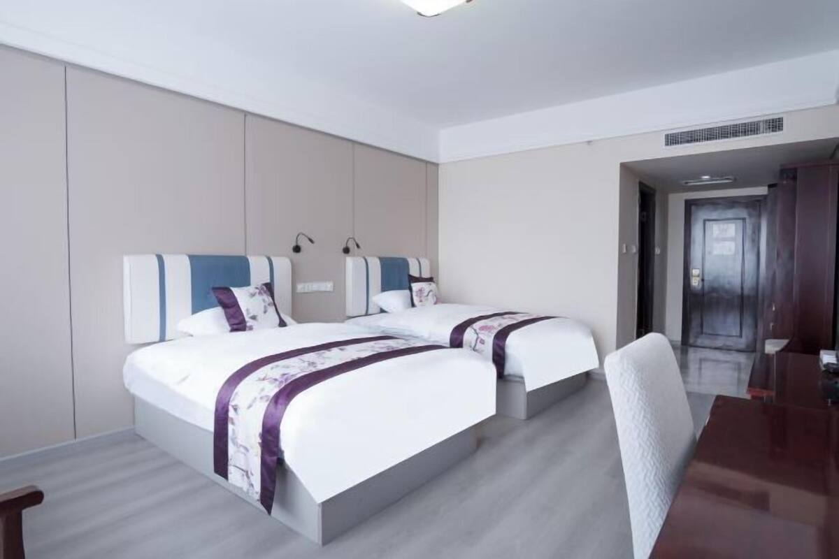 A hotel room with two beds, a desk, and a chair.