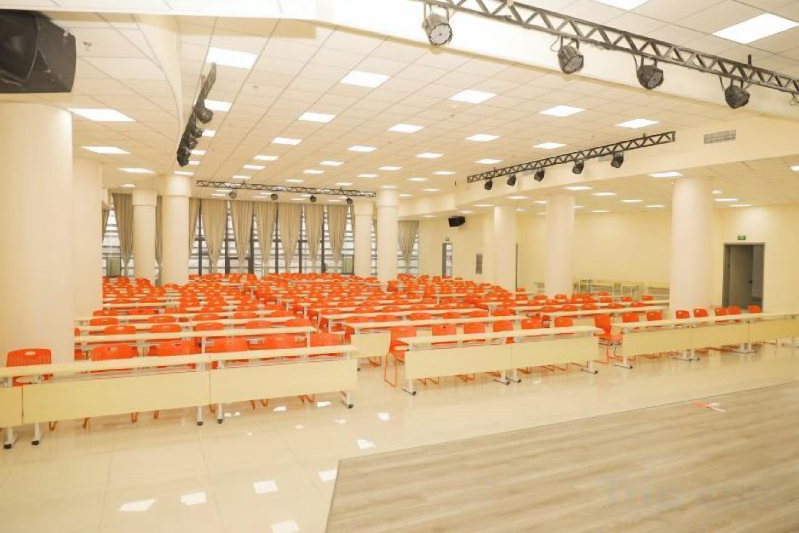 A large auditorium with rows of chairs, a stage with lighting, and a polished floor.