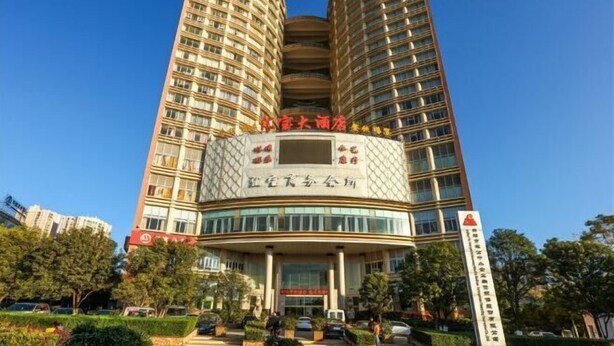Un edificio alto con fachada curva, varios balcones y una entrada central con señalización.