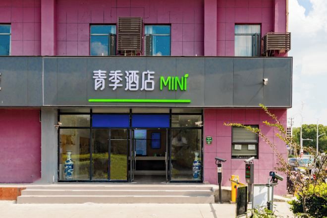 L'entrée d'un hôtel avec une enseigne indiquant « 青季酒店 MINI ».