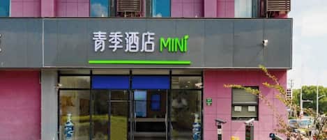 L'entrée d'un hôtel avec une enseigne indiquant « 青季酒店 MINI ».