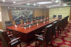 Un salón de conferencias con una larga mesa, sillas y piso alfombrado.