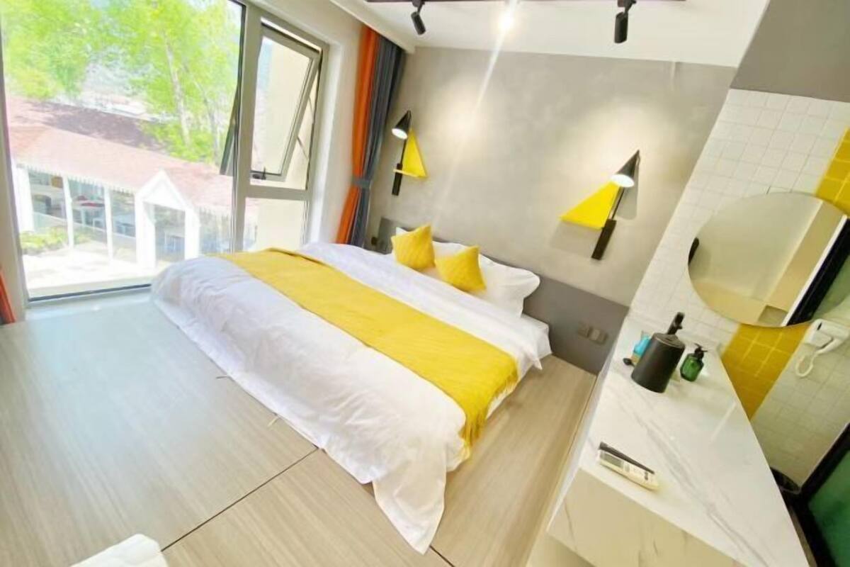 Quarto de hotel com uma cama grande, banheiro com espelho e vista para o exterior.
