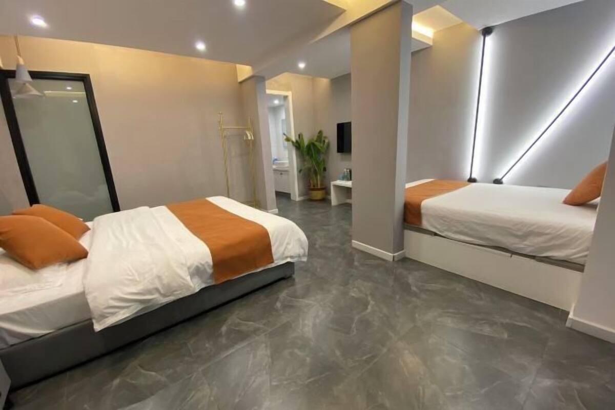 Quarto de hotel moderno com uma cama grande, uma cama menor e uma área de estar.