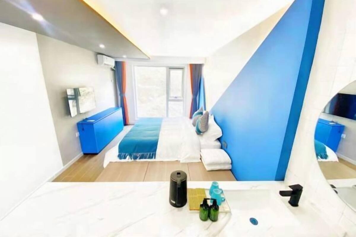 Quarto de hotel moderno com uma cama, uma escrivaninha e vista para o exterior.