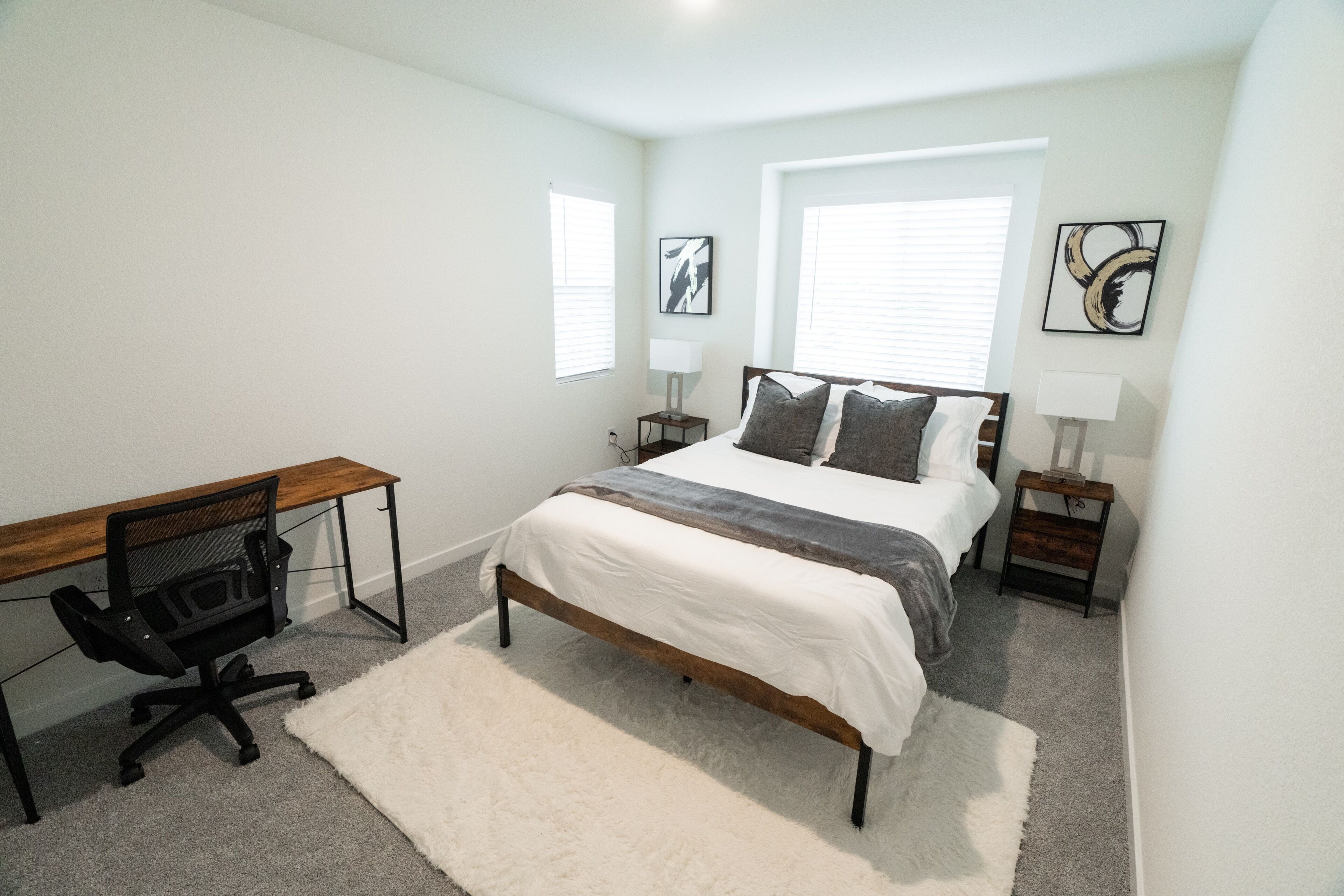 A bedroom with a bed, a desk, and two nightstands.