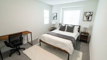 A bedroom with a bed, a desk, and two nightstands.