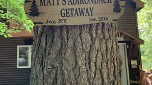 A wooden sign on a tree trunk welcoming visitors to Matt's Adirondack Getaway in Jay, NY, established in 2016.