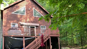 A wooden cabin with a deck, outdoor seating, and a fire pit.