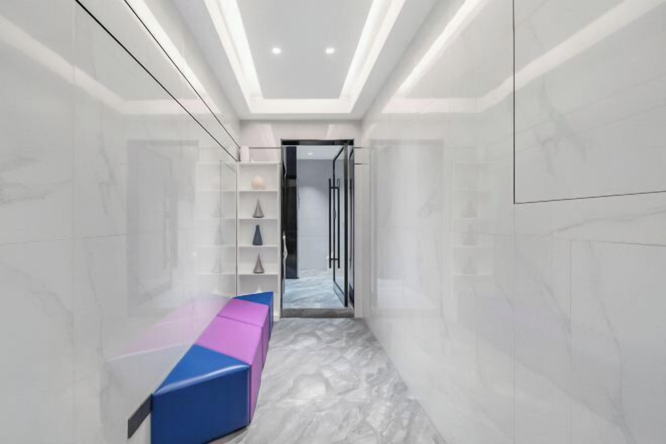 A corridor with a bench, a glass door, and a marble floor.
