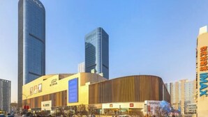 A modern urban building complex with high-rise structures and a curved building with signage.
