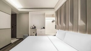 Una habitación de hotel con una cama grande, un escritorio, un tocador y zona de ducha.