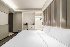 Quarto de hotel com uma cama grande, escrivaninha, toucador e área de chuveiro.