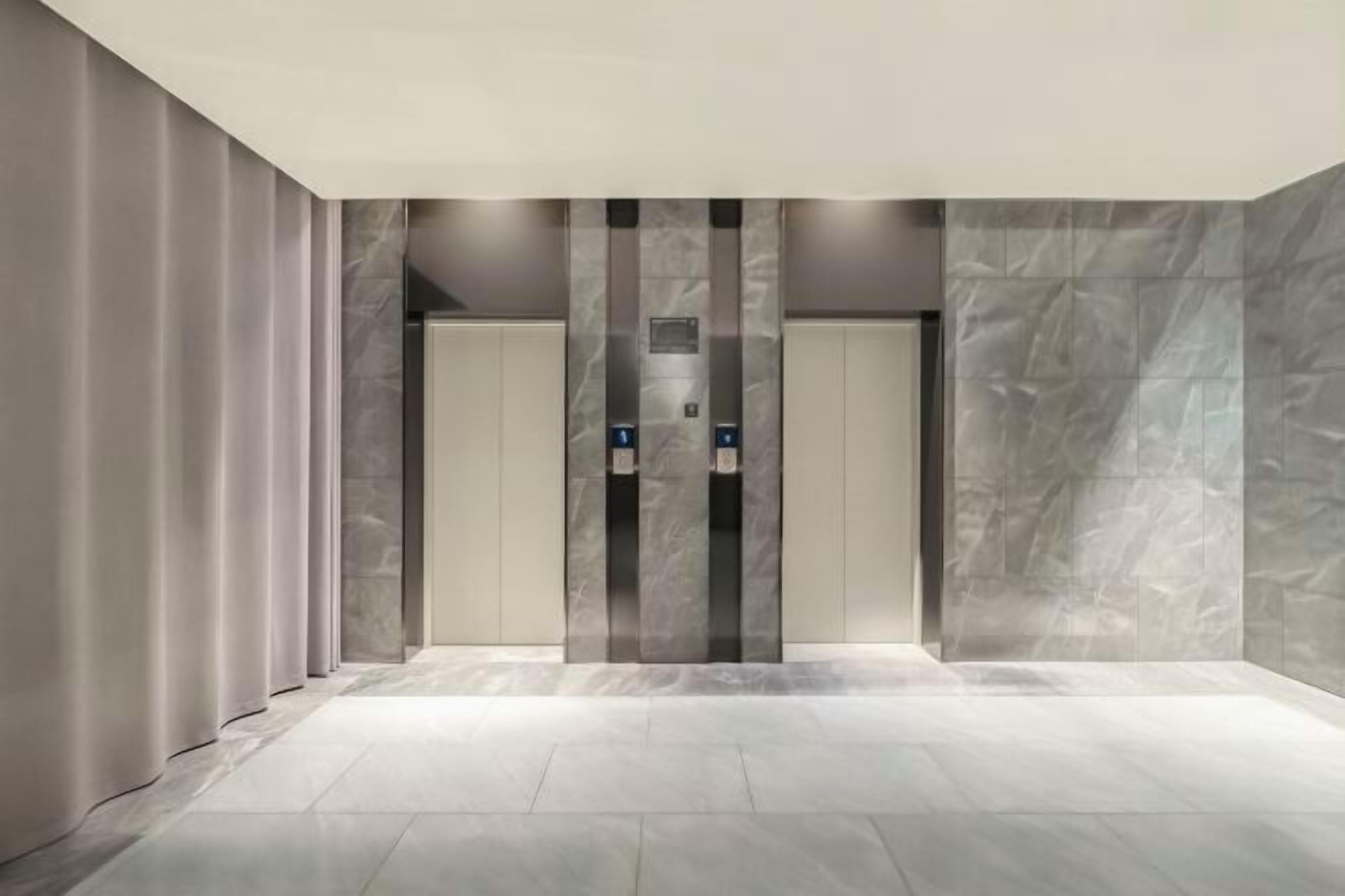 Un espace moderne pour les ascenseurs, avec des murs en marbre et un sol carrelé.