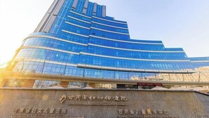 Un moderno edificio hospitalario con fachada de vidrio curva y señalización que indica que se trata del Hospital Provincial de Gansu para Mujeres y Niños.