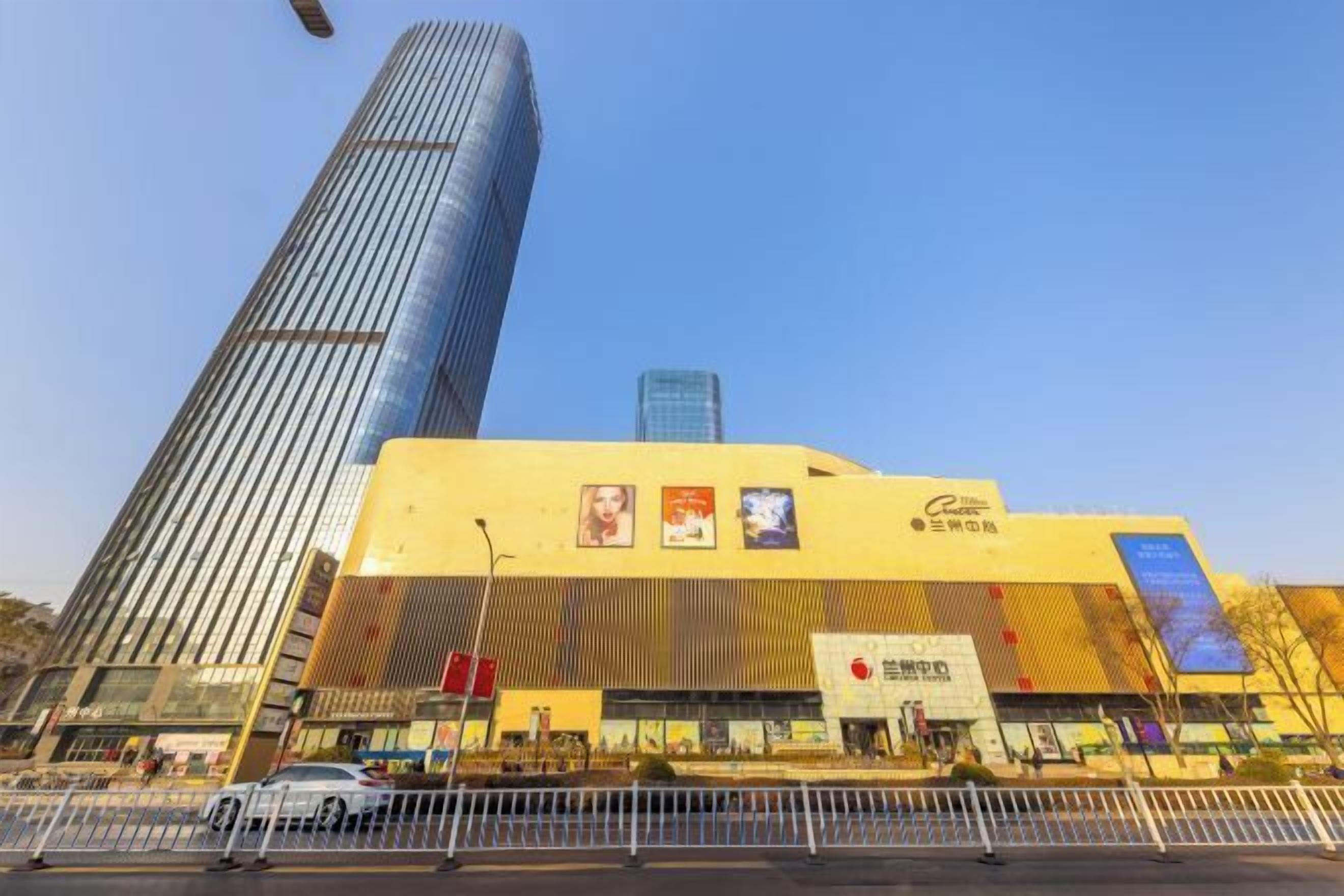 A modern building with a prominent vertical structure and a yellow facade with signage.