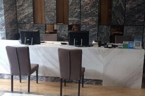 A reception area with a marble counter, two brown chairs, and two computer monitors. - Kaiwang Hotel (Nanjing Mingguo Subway Station Military General Hospital) (Nanjing)