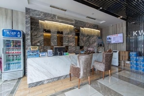 A hotel reception area with a marble counter, two chairs, a beverage dispenser, and a television screen. - Kaiwang Hotel (Nanjing Mingguo Subway Station Military General Hospital) (Nanjing)