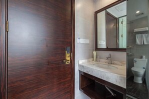 A bathroom with a wooden door, a marble sink, a large mirror, and a toilet. - Kaiwang Hotel (Nanjing Mingguo Subway Station Military General Hospital) (Nanjing)