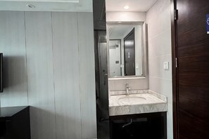 A modern bathroom with a large mirror, a sink, and a dark wooden door. - Kaiwang Hotel (Nanjing Mingguo Subway Station Military General Hospital) (Nanjing)