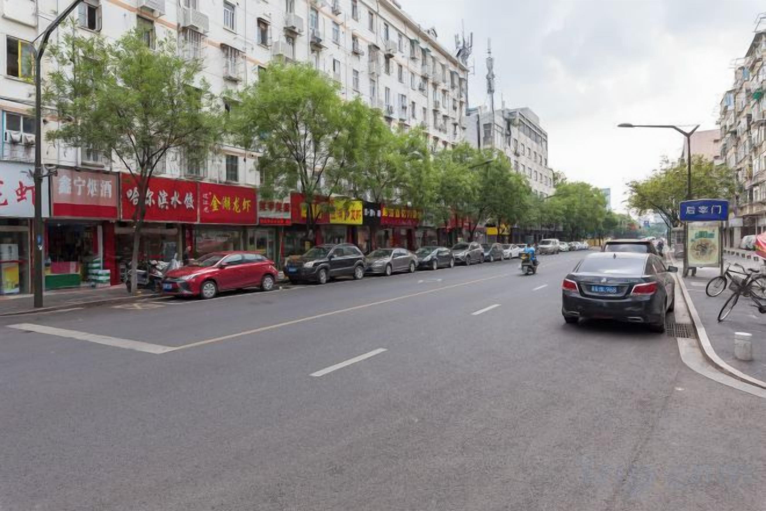 A street with parked cars, trees, and buildings with signage.