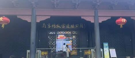 A traditional building entrance with steps leading up to a gate, a signboard, and a red lantern.