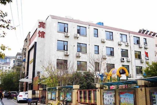 A multi-story building with a white facade, multiple windows, and a visible entrance.
