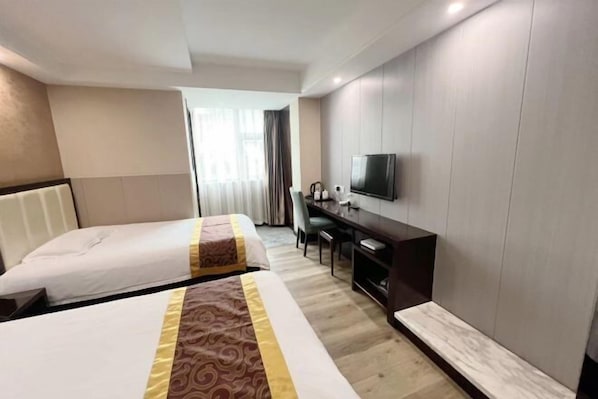 Una habitación de hotel con dos camas, un escritorio, una silla, un televisor y una ventana con cortinas.