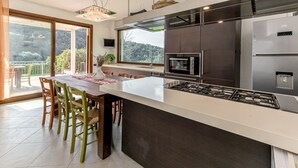 Une cuisine moderne dotée d’un grand îlot central, d’appareils électroménagers intégrés et d’un coin repas avec des chaises.