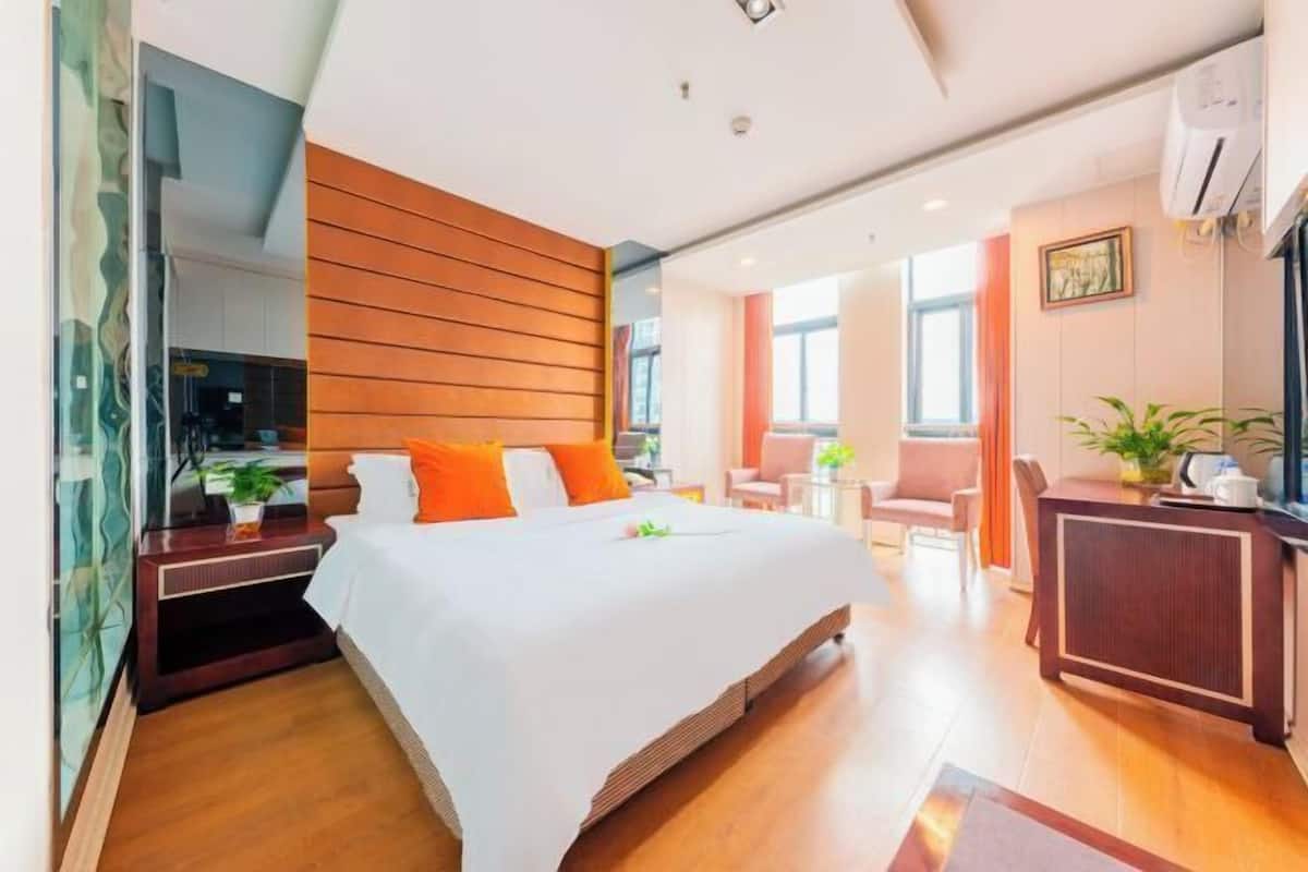Hotellihuone, jossa on sänky, yöpöytä ja työpöytä tuolilla.