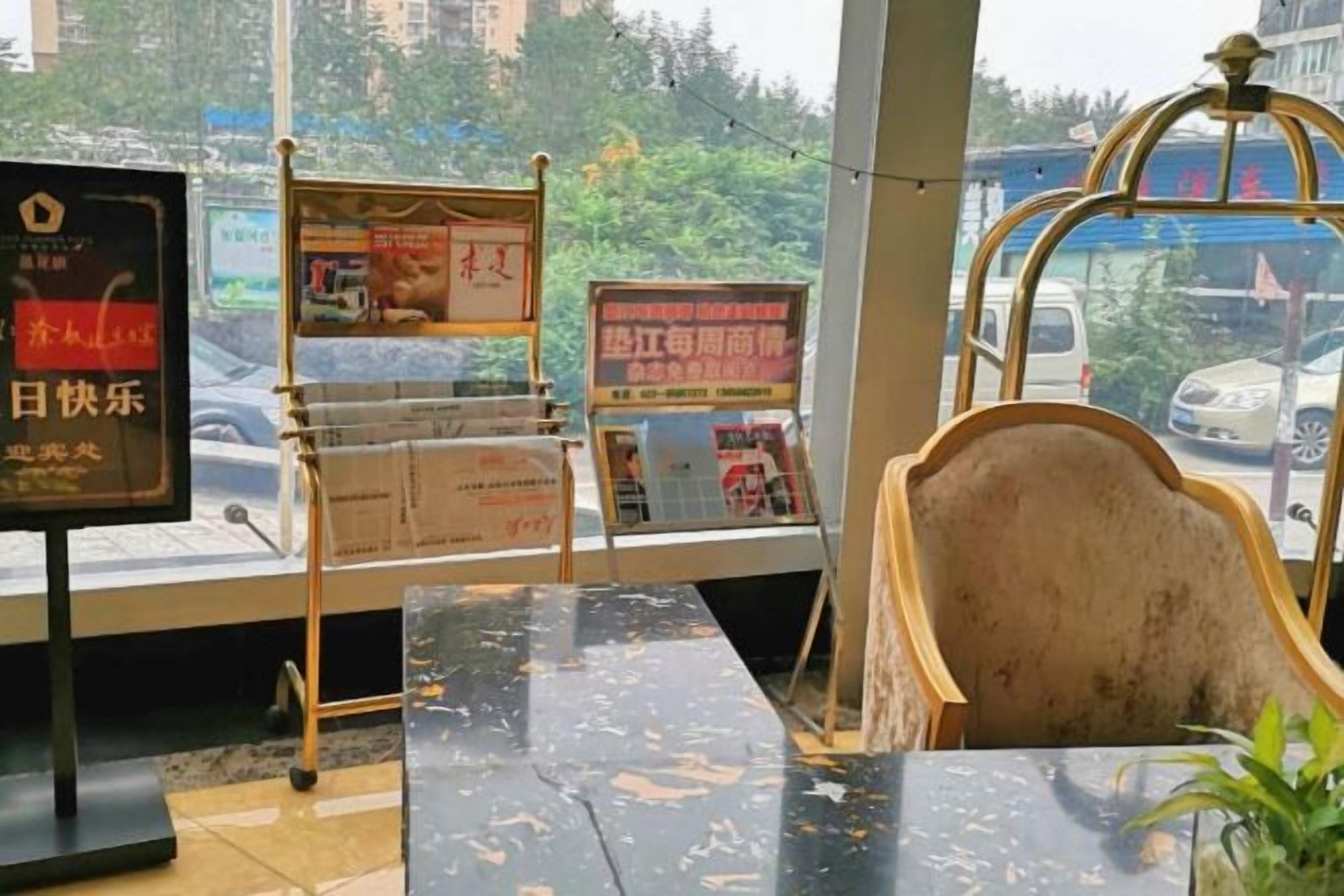 A hotel lobby with a marble reception desk, a wooden chair, and a view of the street outside.