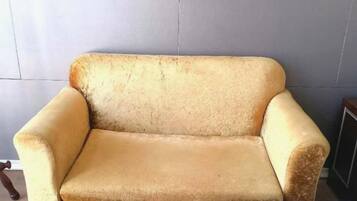 A vintage armchair with a high backrest and armrests, positioned against a plain wall.