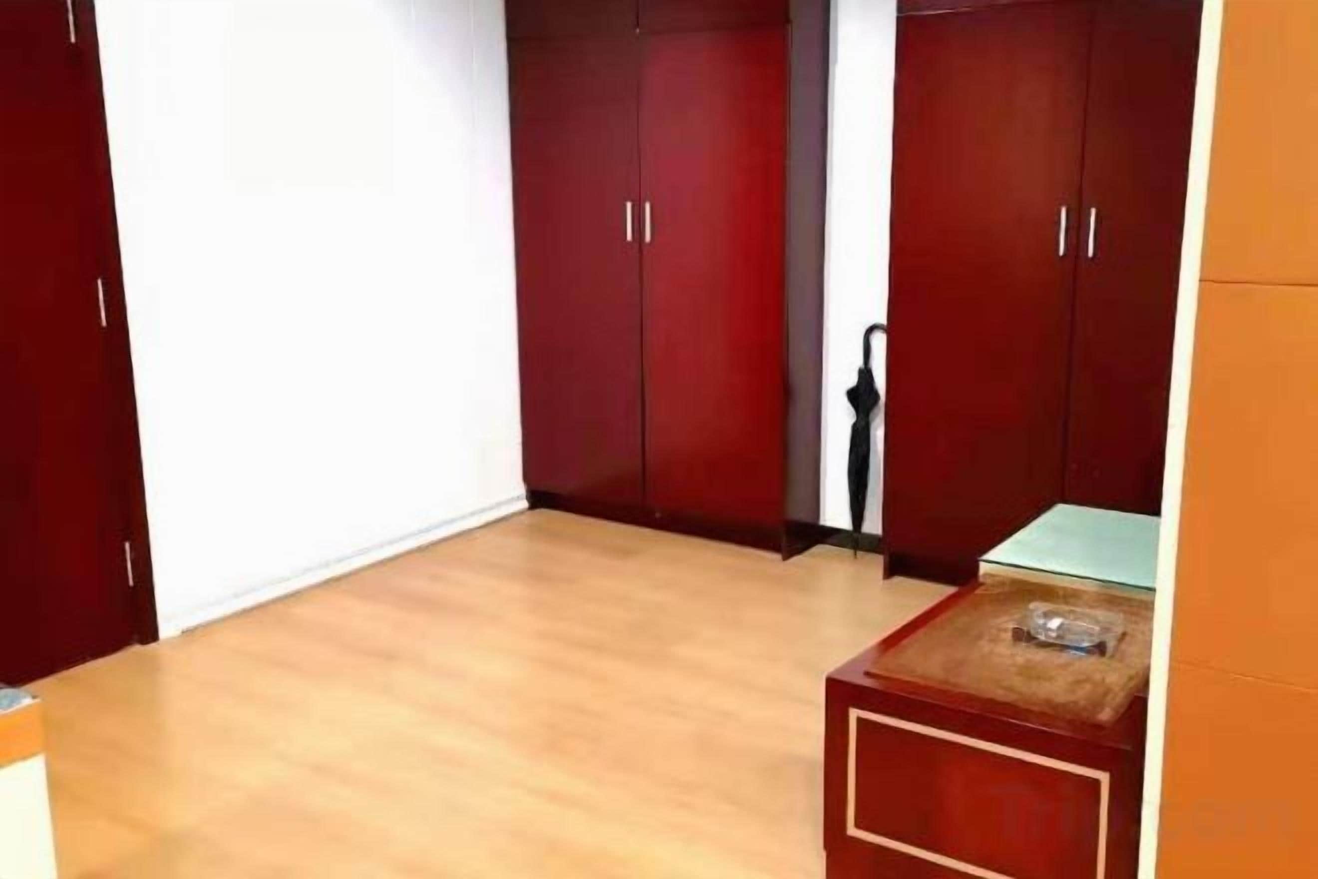 A room with wooden flooring, a small table, and a wardrobe with two doors.