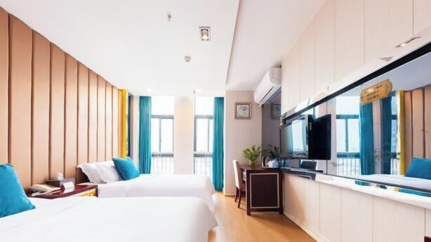 A hotel room with two beds, a kitchenette, a TV, and a large window. - Landing International Hotel (Dianjiang County)