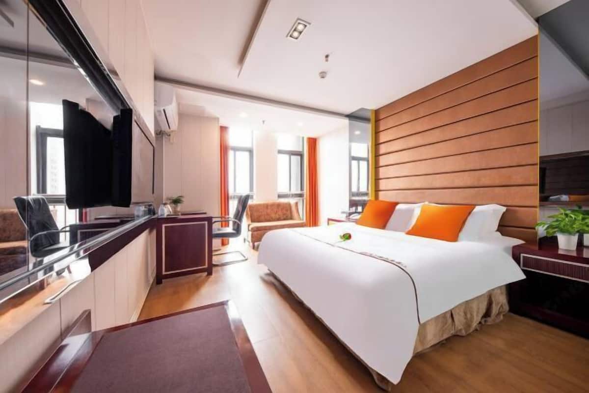 Moderni hotellihuone, jossa on suuri sänky, työpöytä, tuoli ja televisio.
