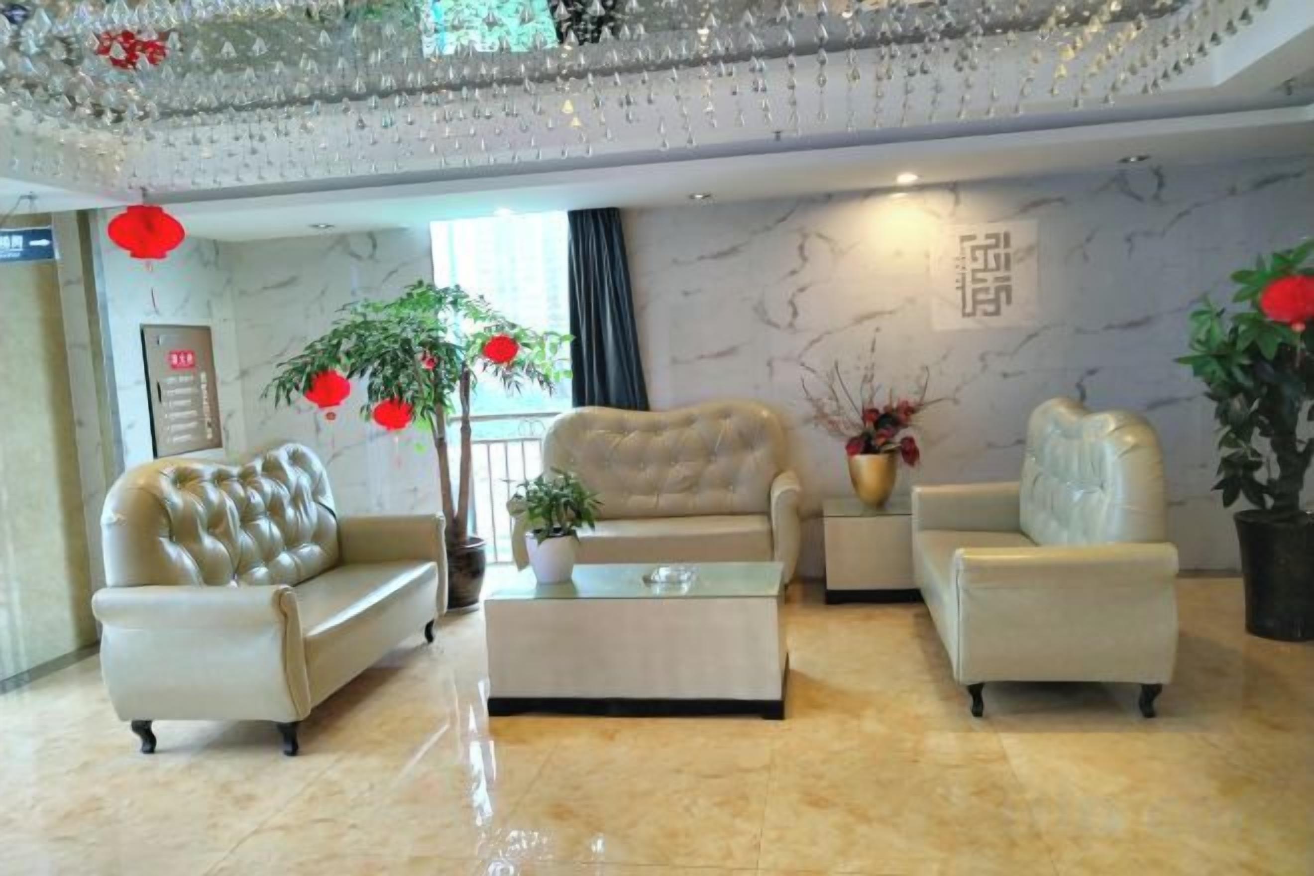 A hotel lobby with a marble floor, leather sofas, a coffee table, and a chandelier.