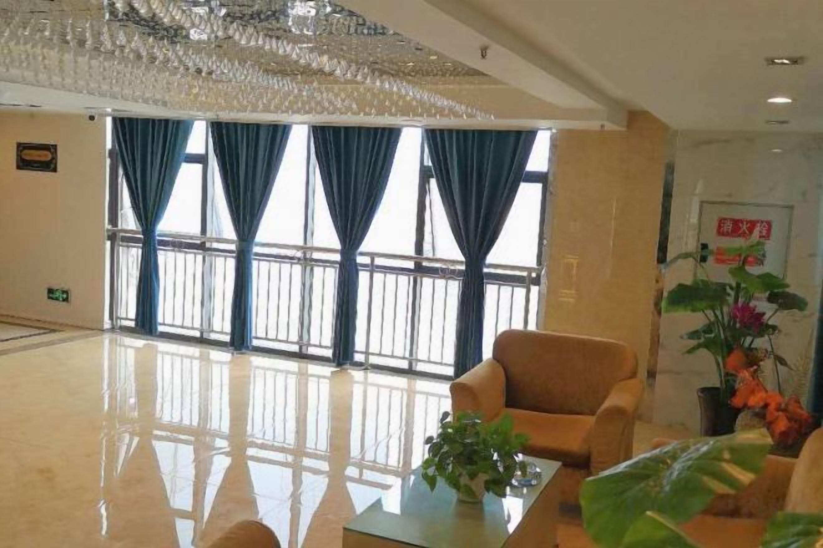 A hotel lobby with a large window, a chandelier, and a seating area.