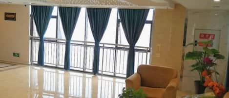A hotel lobby with a large window, a chandelier, and a seating area.
