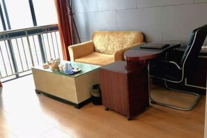 Una habitación con sofá, una pequeña mesa de madera, una silla y una ventana con vistas.