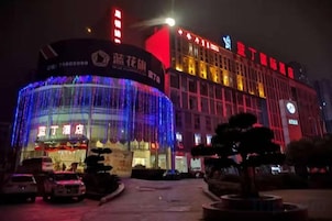 Um hotel com fachada curva notável, sinalização iluminada e entrada bem iluminada.