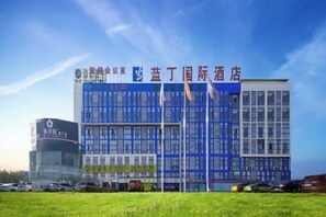 A modern hotel building with multiple floors, large windows, and a prominent sign. - Landing International Hotel (Dianjiang County)