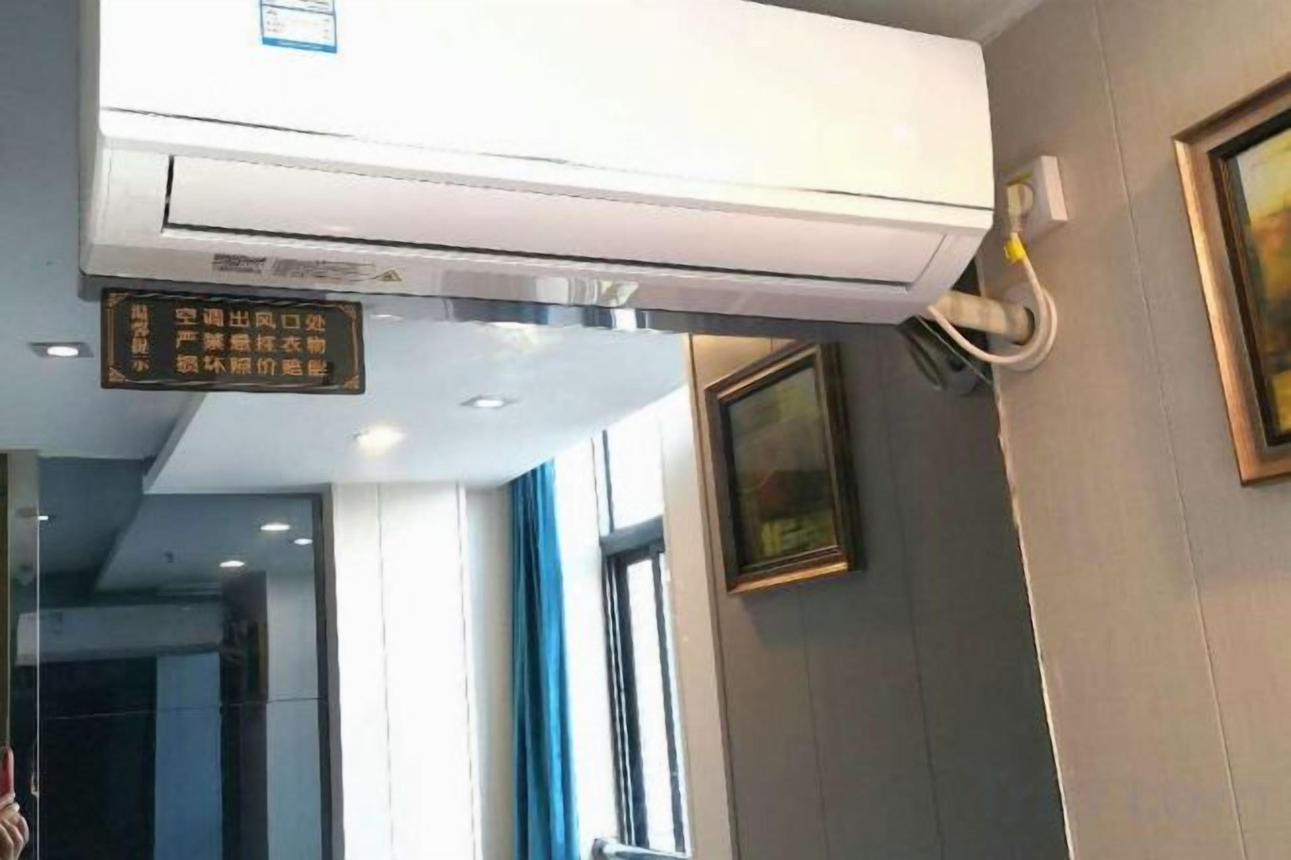 Un appareil de climatisation fixé au mur, doté d’un panneau de commande et d’un tuyau.